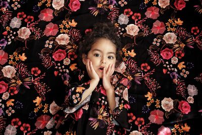 Portrait of cute girl against floral curtain