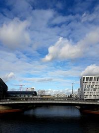 Bridge over river in city against sky