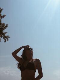 Low angle view of carefree woman standing against sky