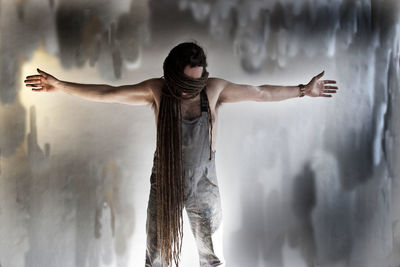 Man with dreadlocks standing against abandoned wall