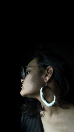 Portrait of a young woman looking away over black background
