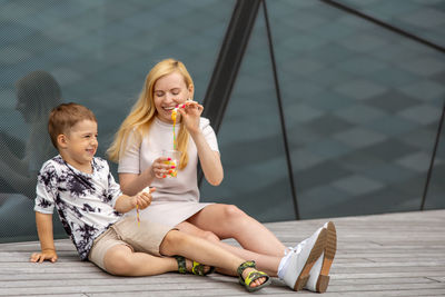 Happy blond woman and little boy sitting on terrace and eating sweets. mother and son