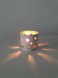 Close-up of illuminated light on table against wall