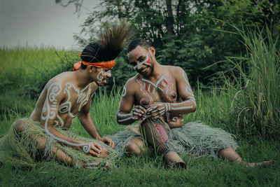 Full length of shirtless man sitting on field