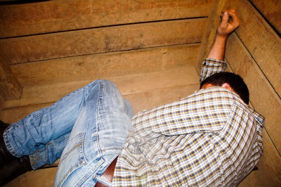 High angle view of young man sleeping on wooden floor