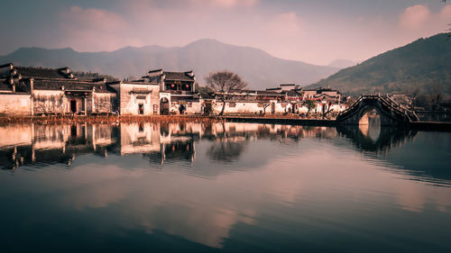 Reflection of houses and river against sky