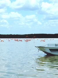 Boats in sea against cloudy sky