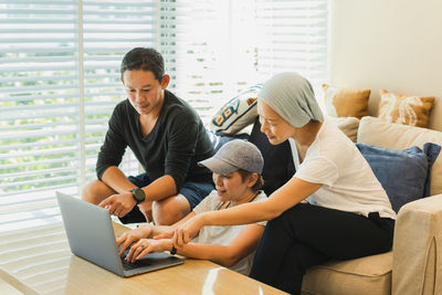 Young woman using laptop while sitting on sofa at home