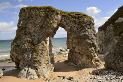 Rock formation by sea against sky