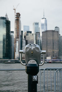 Close-up of coin-operated binoculars against buildings in city