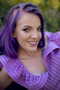 Teenage girl with dyed purple hair and a nose piercing in the grass  in a short dress
