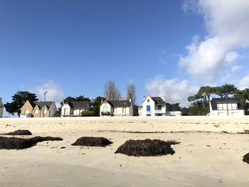 Houses on beach by buildings against blue sky