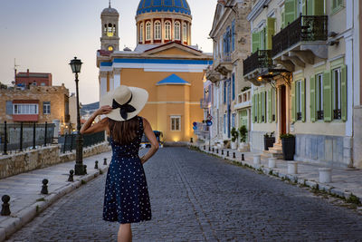 Rear view of young woman with arms raised standing in city