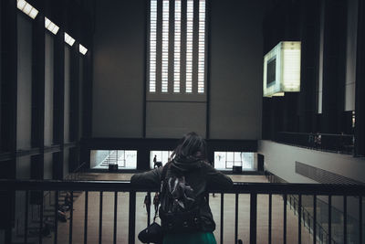 Rear view of woman standing against window in building