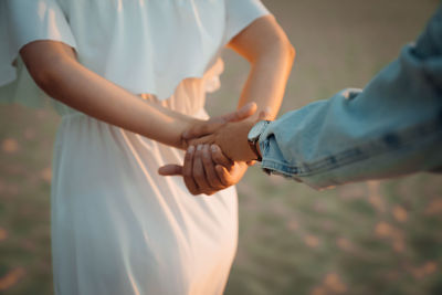 Midsection of couple holding hands