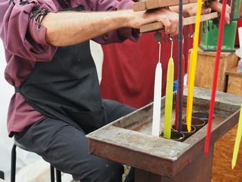 Midsection of man making candles while sitting on chair