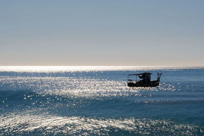 Silhouette boat in sea against clear sky