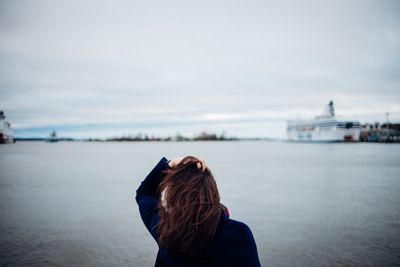 Rear view of woman at beach against sky