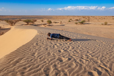 A man doing a plank at a sand dune at north horr sand dunes, marsabit, kenya