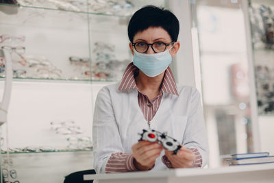 Portrait of young woman holding eyeglasses