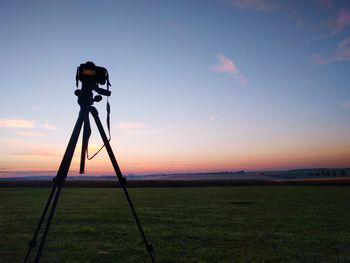 Cross on field against sky during sunset