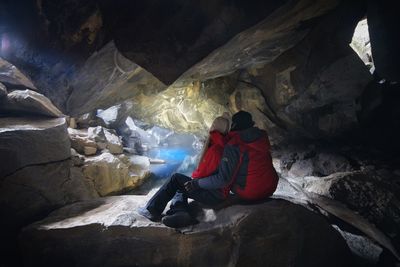 Rear view of man sitting on rock