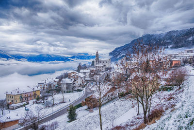 Snow covered buildings and mountains against sky