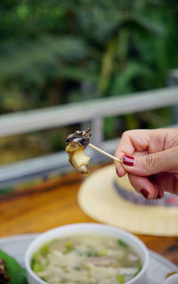 Close up of woman's hand picking slugs from a cooked escargot to eat