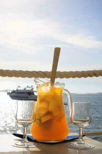 Close-up of drink on table by sea against sky