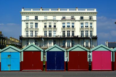 Built structure with beach huts on seafront  against blue sky