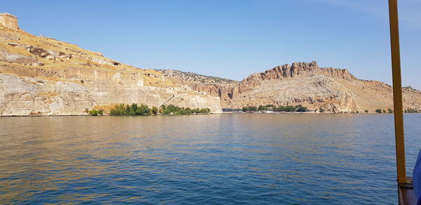 Scenic view of river and mountains against clear blue sky