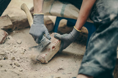 A young man cleans bricks with an axe.