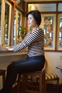 Side view of woman sitting on chair at home