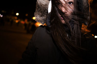 Thoughtful young woman wearing hooded jacket at night