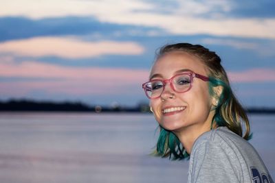 Portrait of smiling young woman against sky