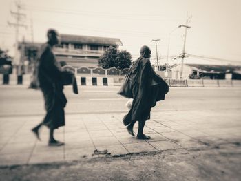 Rear view of people walking on street in city