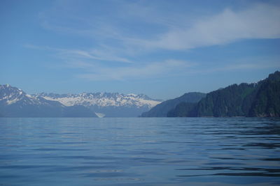 Scenic view of sea and snowcapped mountains against sky