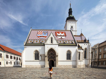 Rear view of woman by building against sky