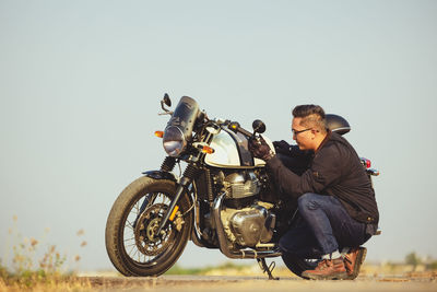 Motorcycle driver in a helmet and leather jacket stands on the road next to a sports motorcycle