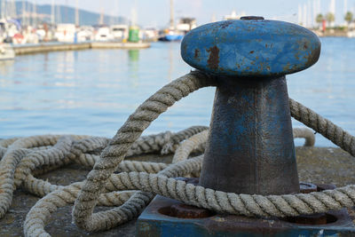 Close-up of rope by bollard on pier