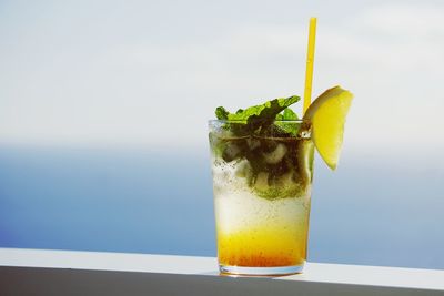 Close-up of drink on railing against sea