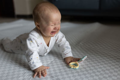 Portrait of cute baby girl on bed at home