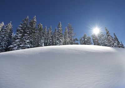 Snow covered land against clear blue sky