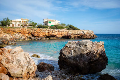 Rocks on beach by sea against sky