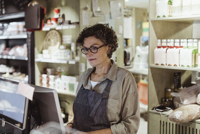 Confident sales woman working on computer in deli store