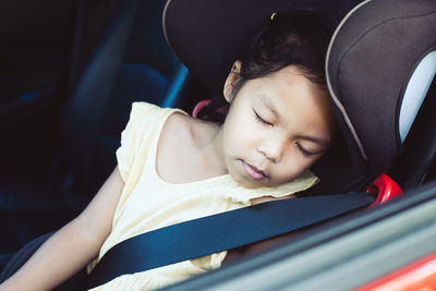 High angle view girl sleeping in car seen through window