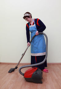 Full length of woman cleaning house with vacuum cleaner