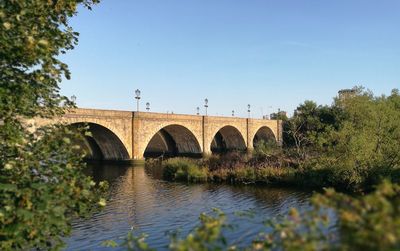 Arch bridge over river against clear sky