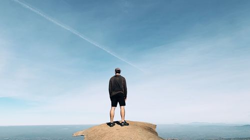 Rear view of man standing on mountain against sky