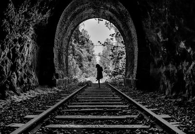 Rear view of silhouette woman standing on railroad track